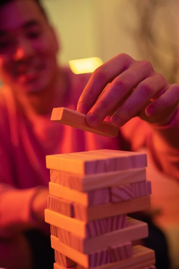 person holding brown wooden blocks over a pile